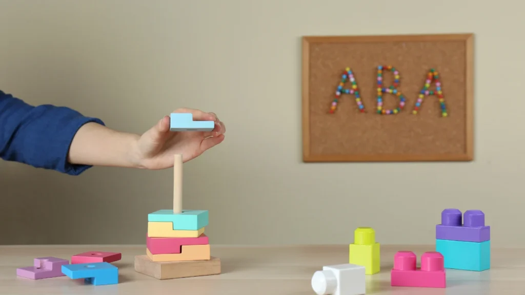 Child stacking wooden blocks on a peg to develop fine motor skills