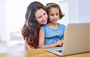 Mother supporting daughter during online learning on a laptop